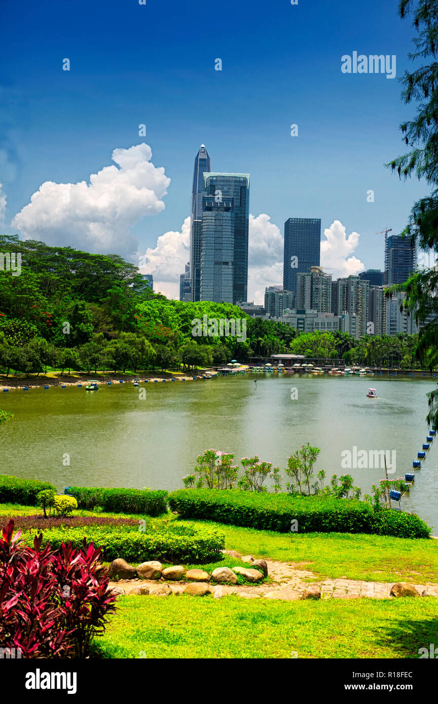 The shenzhen city skyline in the background of a manmade lake inside of Lianhuashan park in Shenzhen china on a sunny blue sky day. Stock Photo