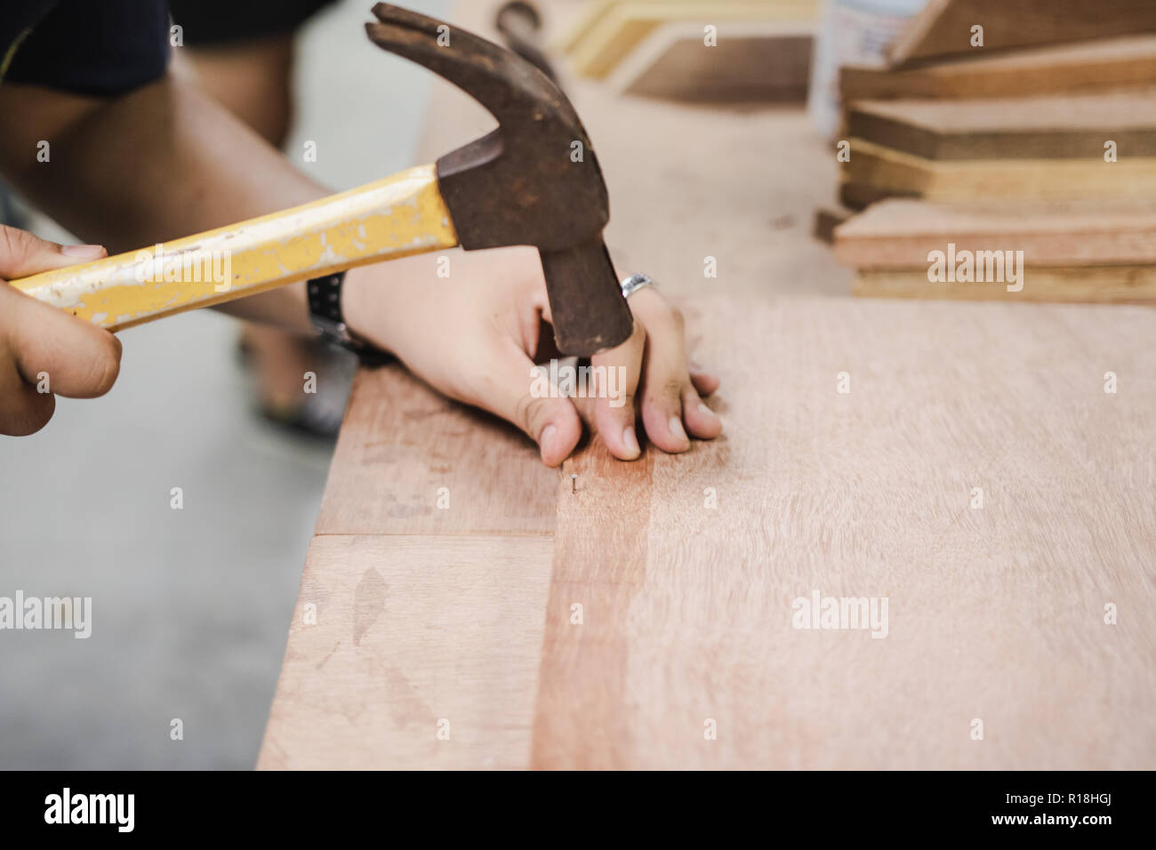 Thai Engineering Student hit a nail using hammer in engineering workshop class Stock Photo