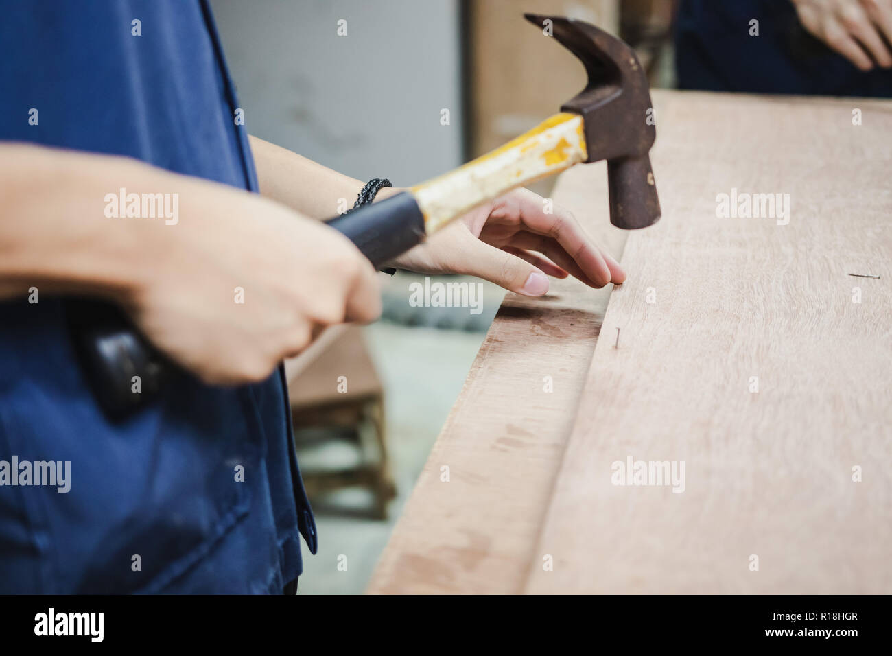 Thai Engineering Student hit a nail using hammer in engineering workshop class Stock Photo