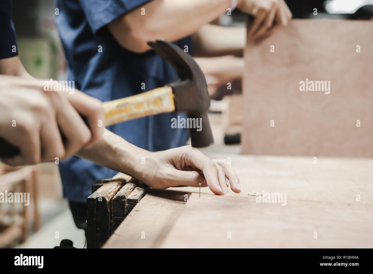 Thai Engineering Student hit a nail using hammer in engineering workshop class Stock Photo
