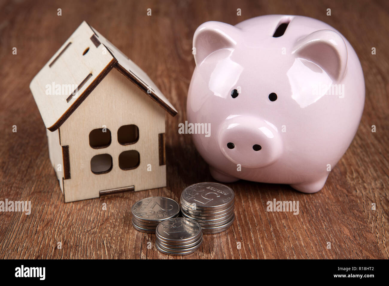 wooden miniature house and pink piggy bank with Russian ruble coins ...