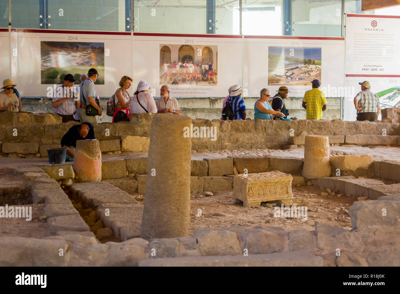 4 May 2018 Pilgrims inspect the restoration work on a 1st century synagogue at the ancient village of Magdala in Galilee Israel. A tradesman continues Stock Photo