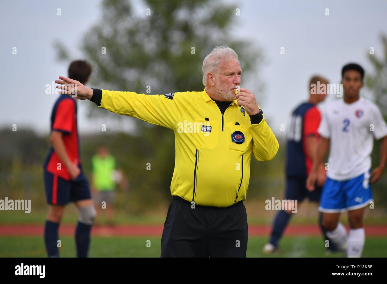 Referee whistling while signaling the direction of play following a