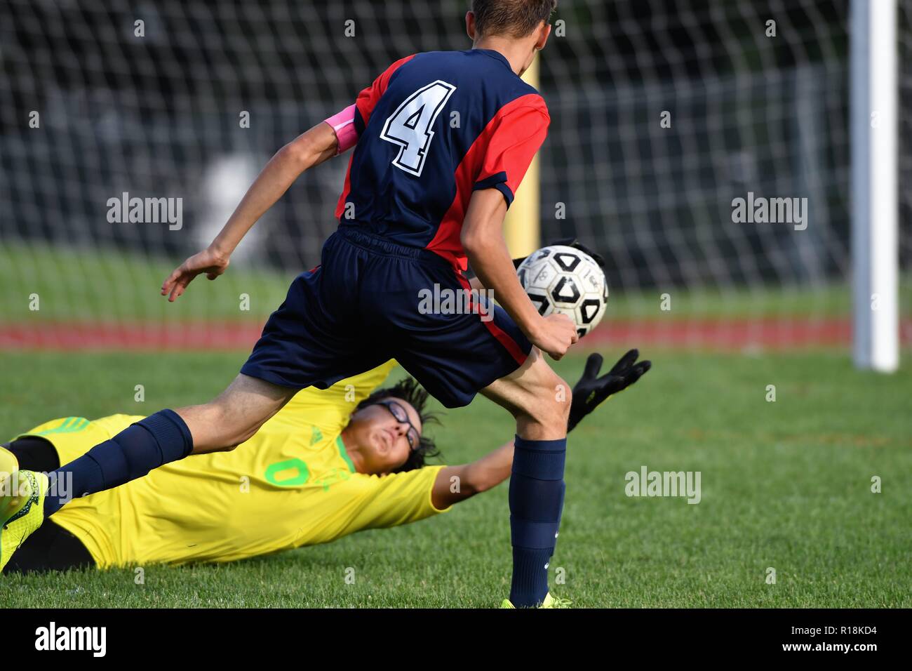 Keeper making a diving stop on a shot and preventing a rebound from a closing opposing forward. USA Stock Photo