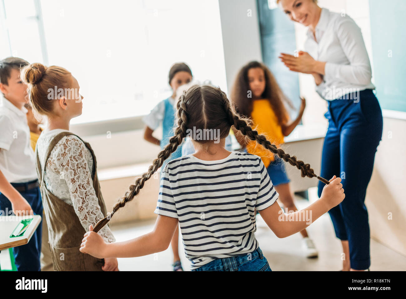 group of multiethnic classmates standing around teacher at classroom Stock Photo