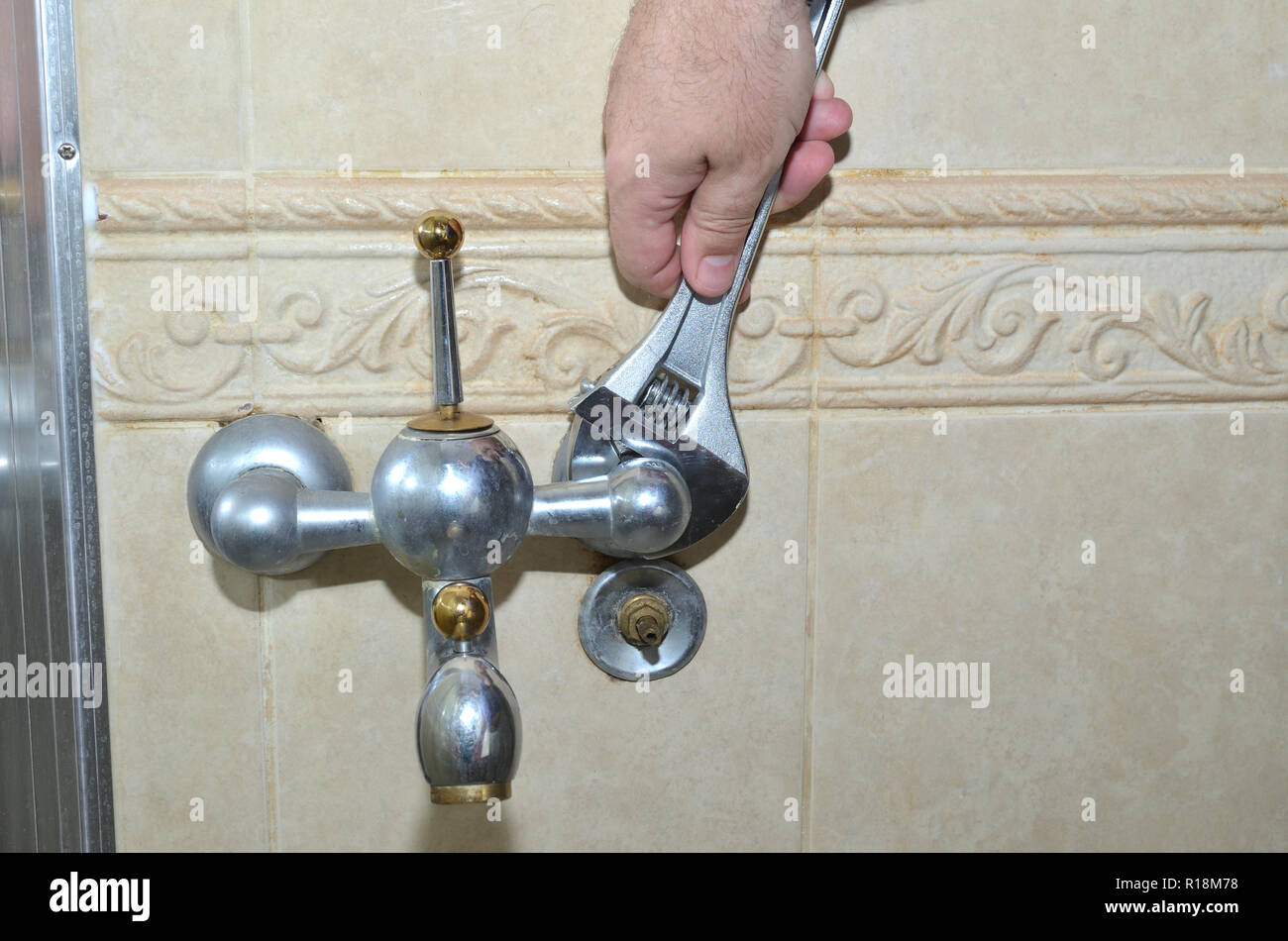 Unscrewing an old bathroom faucet with a wrench Stock Photo