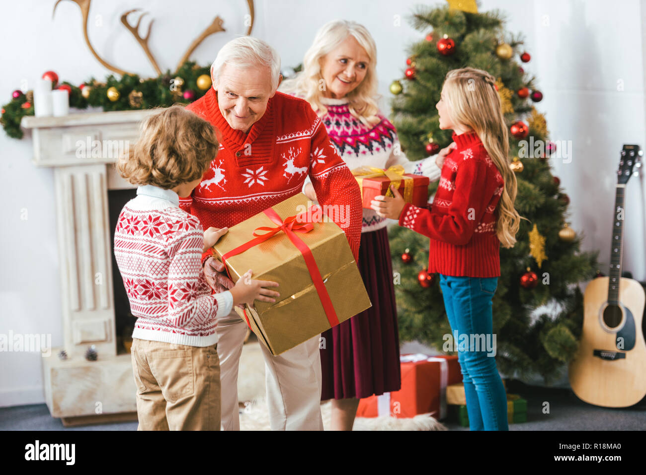smiling grandparents and giving gift boxes for kids on christmas Stock