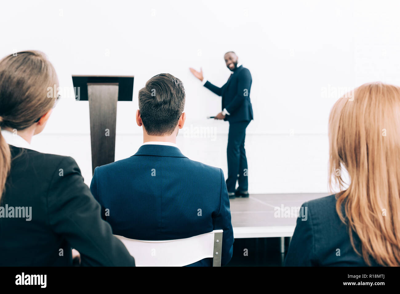 selective focus of smiling african american speaker pointing on screen