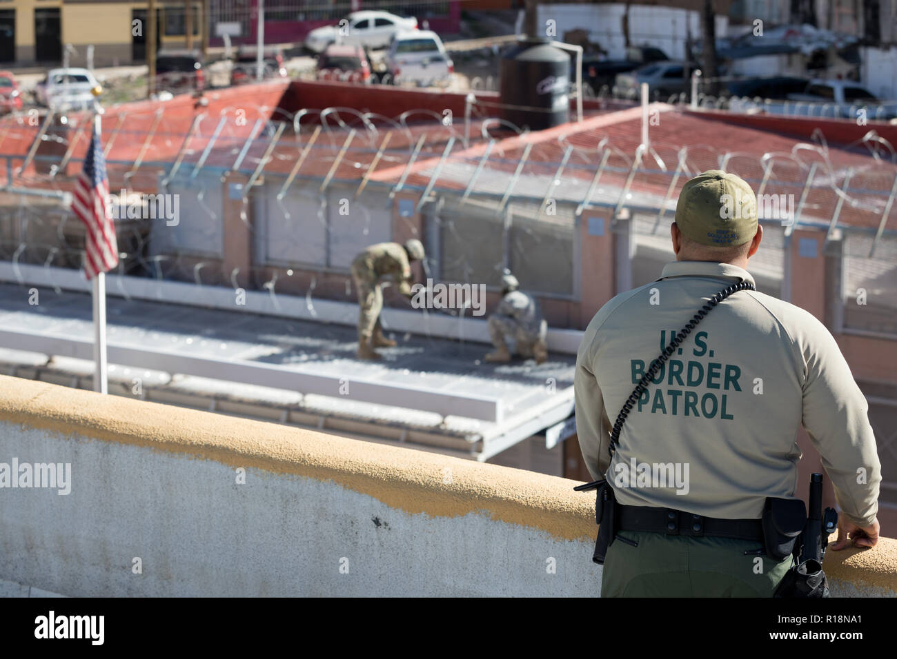 A U.S. Border Patrol Agent watches as soldiers from the U.S. Army 36th Engineer Brigade install concertina wire at the Morley Gate Pedestrian Port November 7, 2018 in Nogales, Arizona. The troops are deploying to the U.S. - Mexico border by order of President Donald Trump to intercept the Honduran migrant caravan. Stock Photo