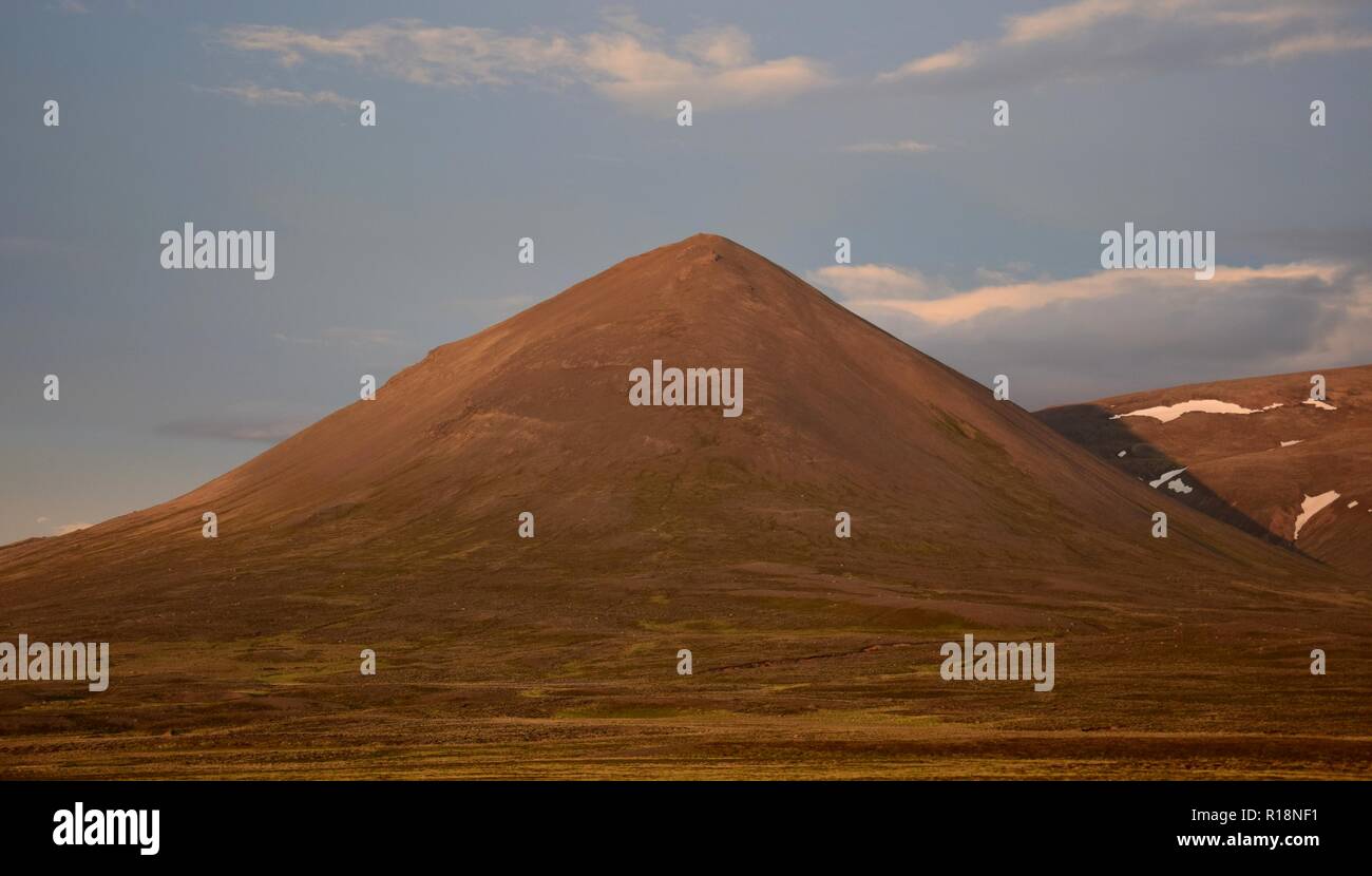 A midsummer night in Iceland. A mountain is glowing in the midnight sun. The Svinadalsfjall near Blönduos. A light blue sky. Stock Photo