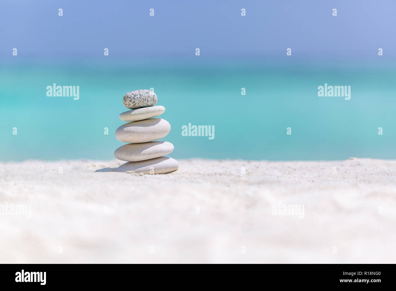 Zen stones on tropical beach for perfect meditation. Stones pyramid on soft sandy beach inspirational, stability, zen, relaxation, harmony, balance Stock Photo