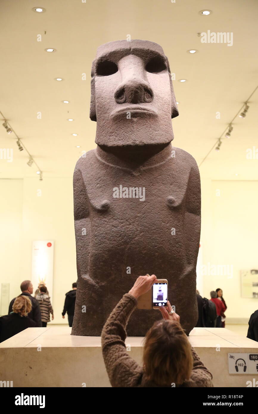 Woman taking a photo with her phone of the basalt-made statue from the ...