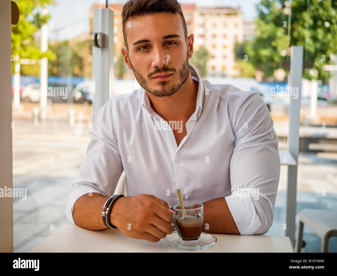 Attractive Young Man Drinking Coffee while Sitting in a Bar with Serious Expression Stock Photo