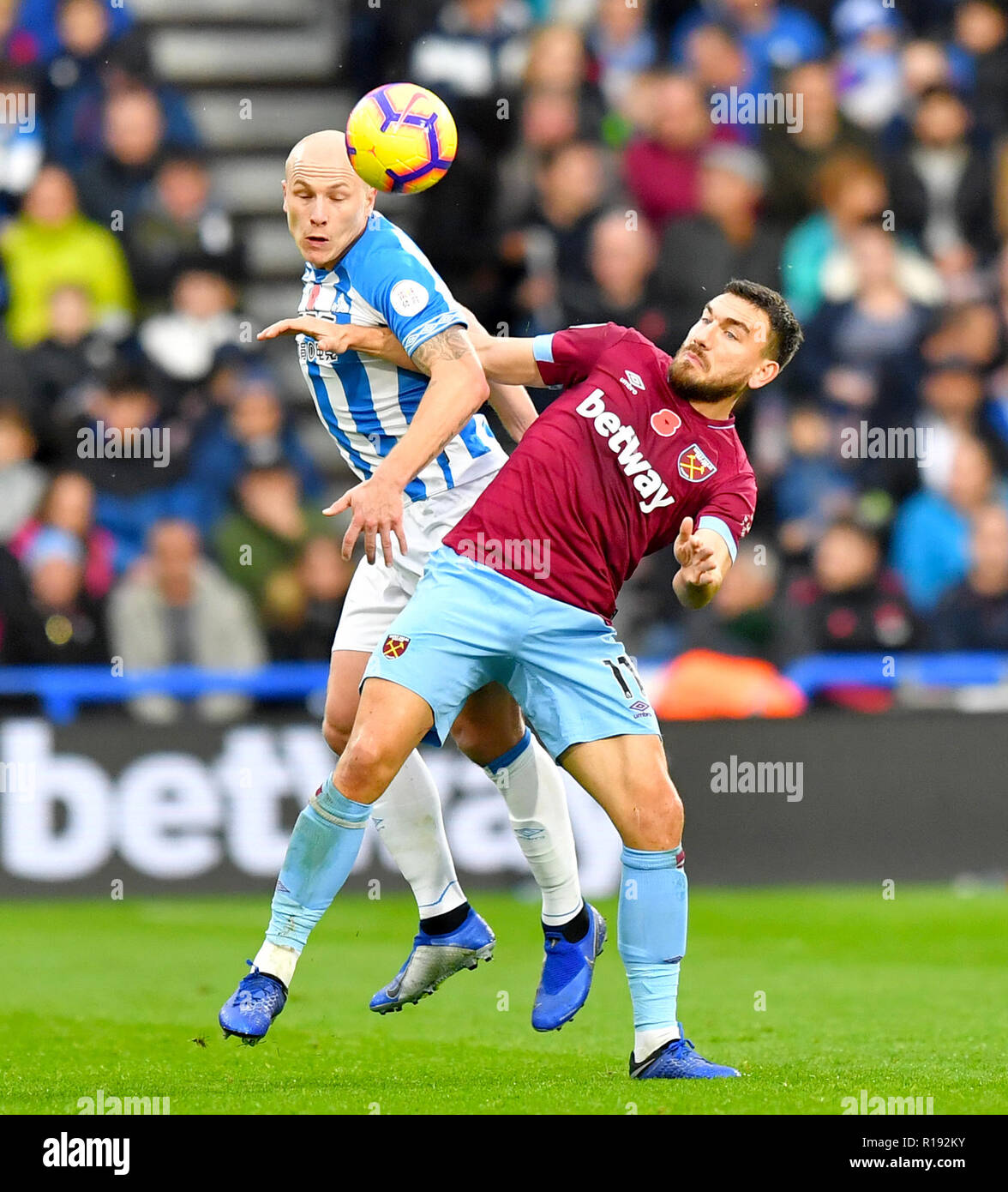 Huddersfield Town's Aaron Mooy (left) and West Ham United's Robert Snodgrass battle for the ball during the Premier League match at the John Smith's Stadium, Huddersfield. Stock Photo