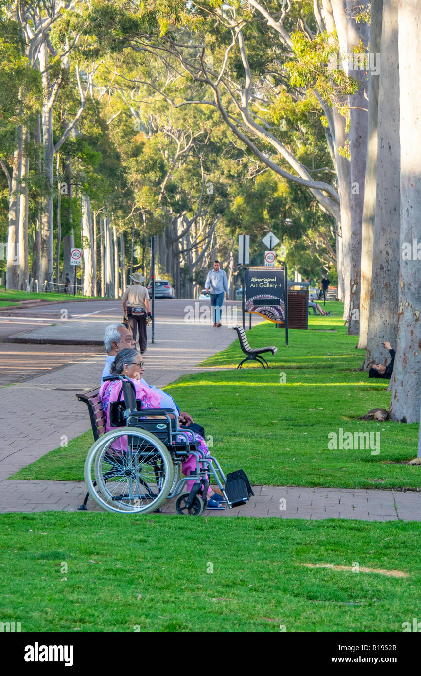 Elderly couple with a wheelchair sitting on a bench in Fraser Avenue Kings Park Perth Western Australia Stock Photo