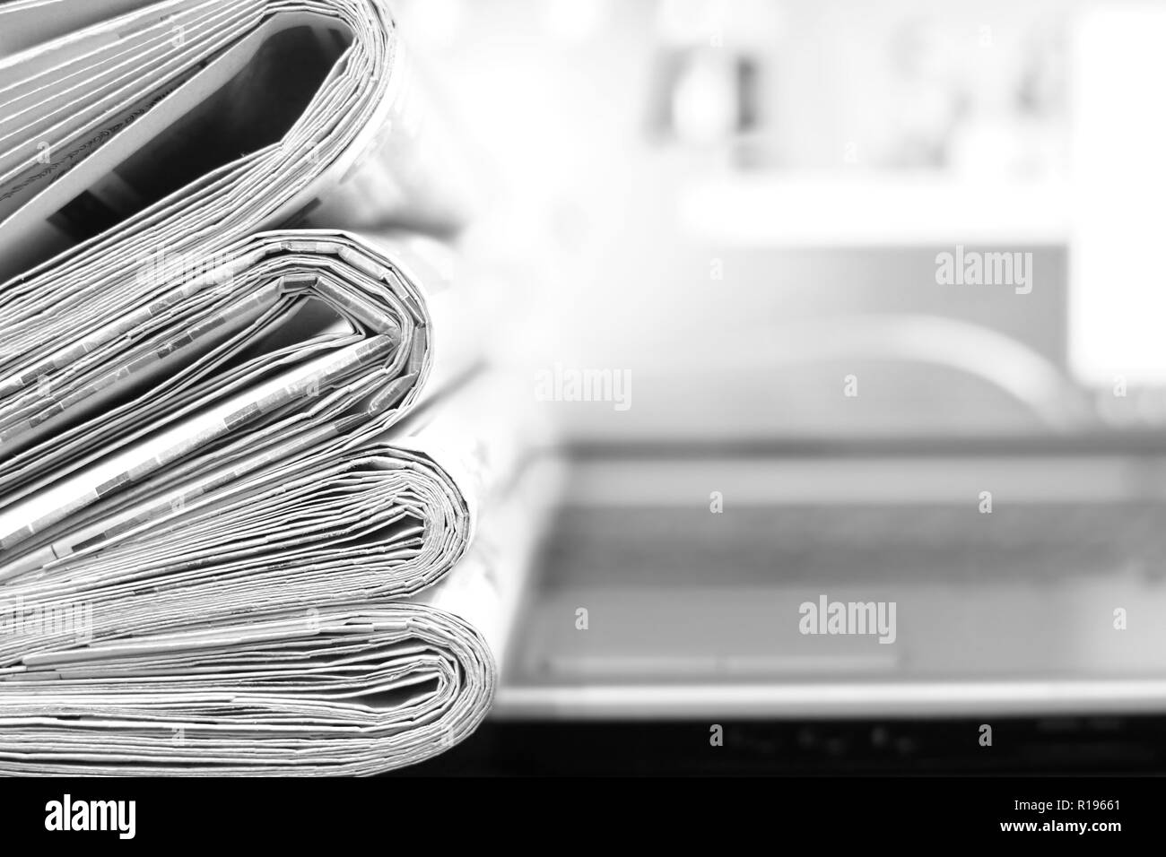 Pile of fresh morning newspapers on the computer. Latest financial and business news in daily paper. Pages with headlines, articles. Stacked journals Stock Photo