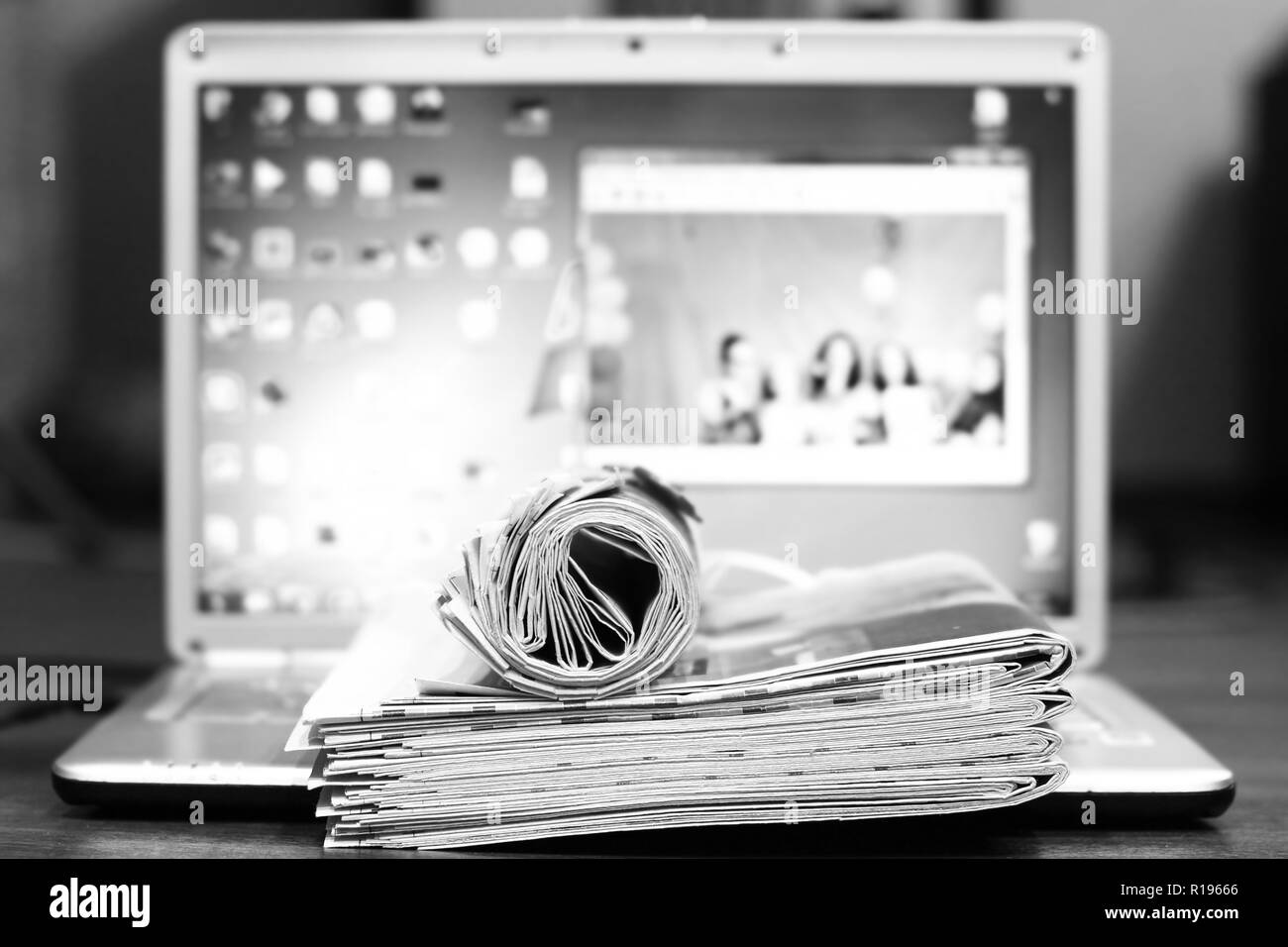 Stack of newspapers and laptop. Journals with news and computer. Papers with headlines, articles and screen. Different sources of information Stock Photo