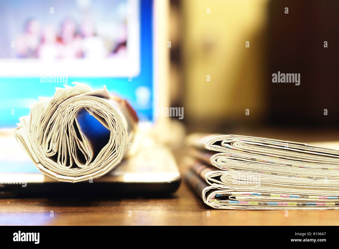 Stack of newspapers and laptop. Journals with news and computer. Papers with headlines, articles and screen. Different sources of information Stock Photo