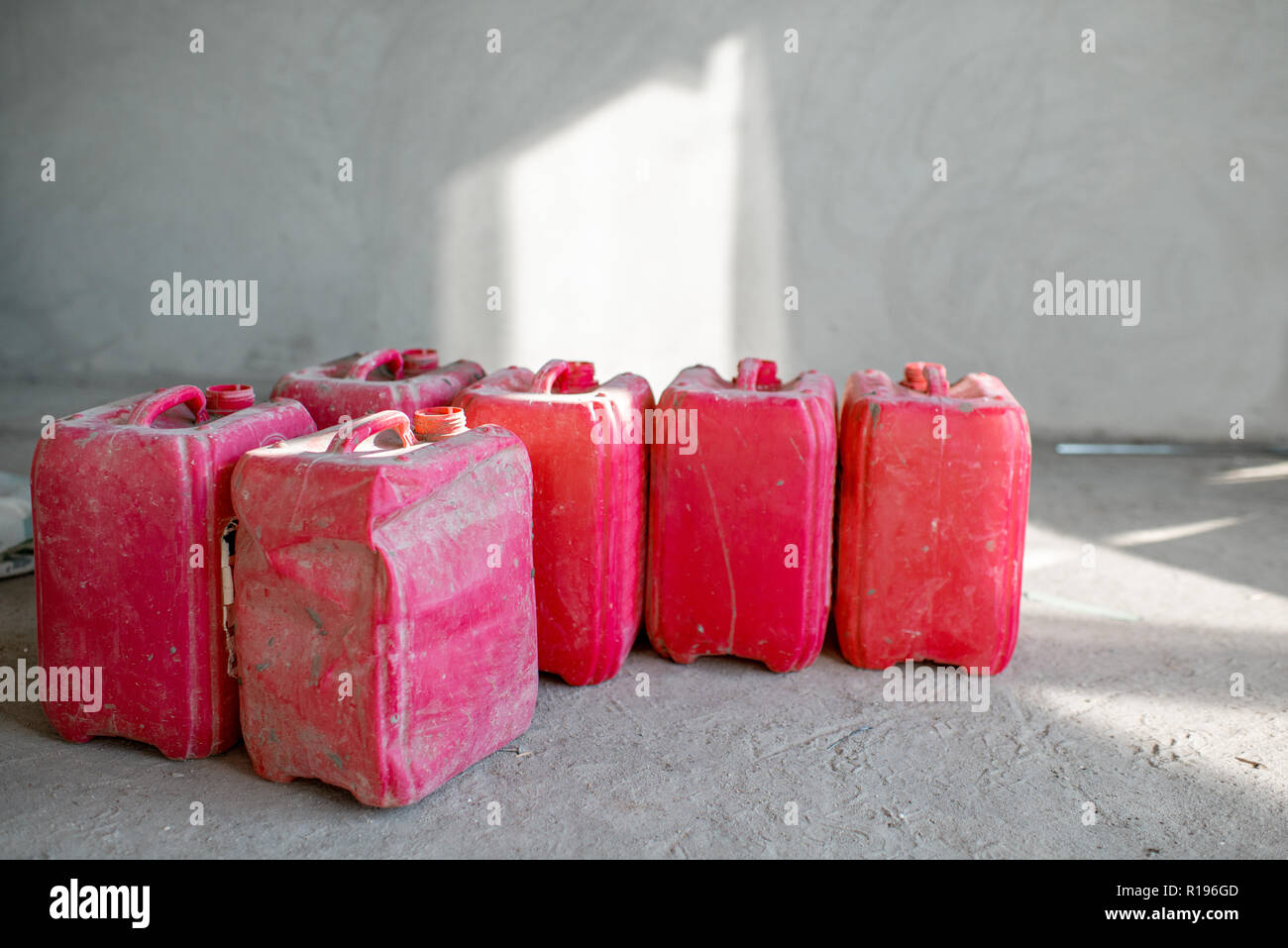 Red used canisters on the construction site indoors on the grey wall background Stock Photo