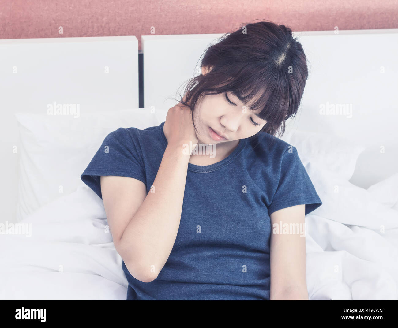 Asian woman back pain and sit on bed in bedroom in the morning Stock