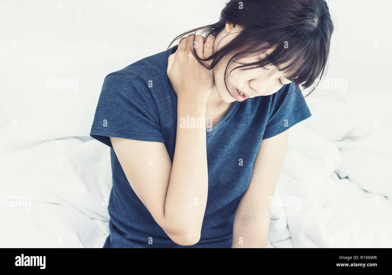Asian woman back pain and sit on bed in bedroom in the morning Stock