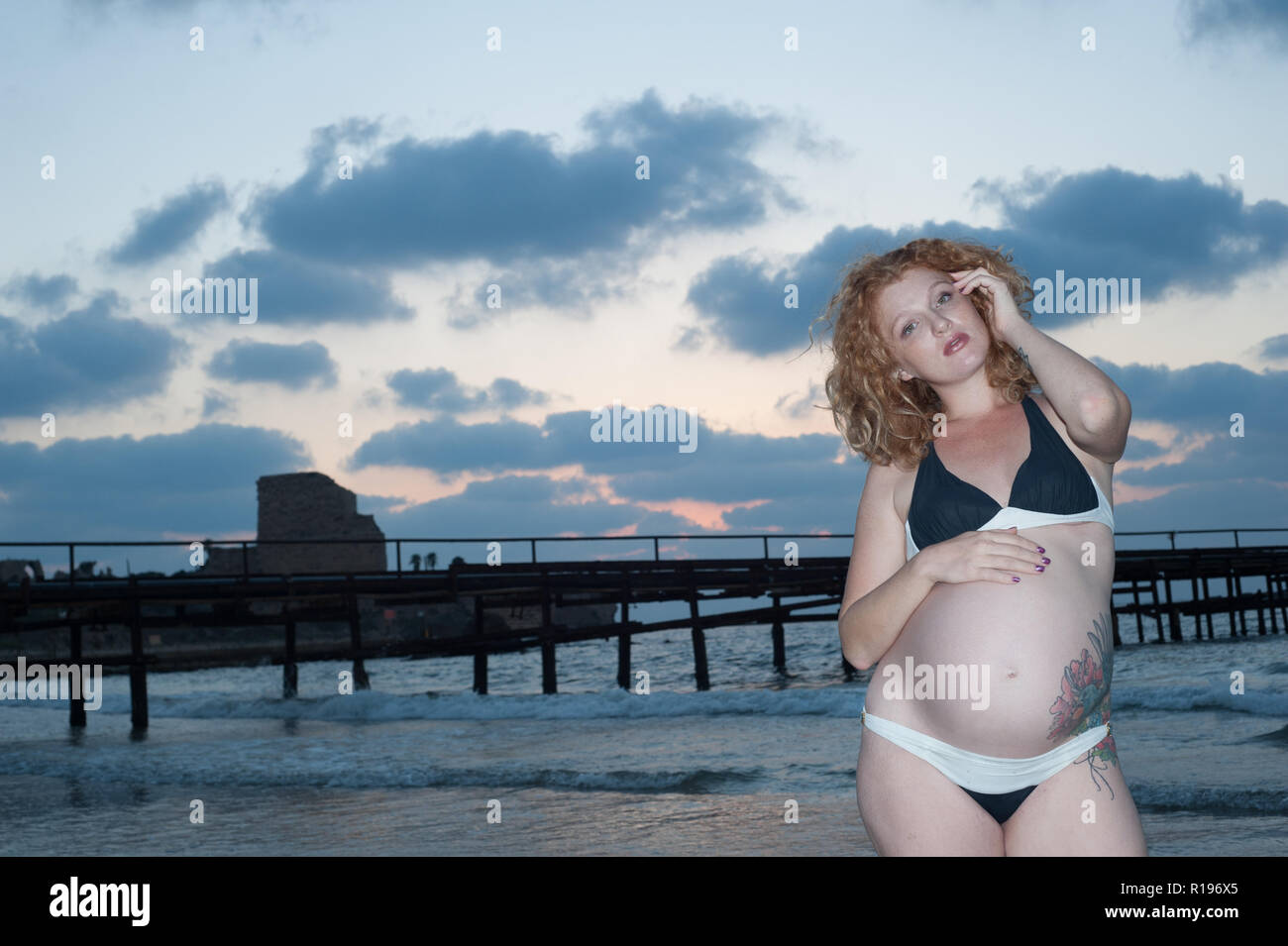 pregnancy woman stand on quay, against cloudy sky Stock Photo