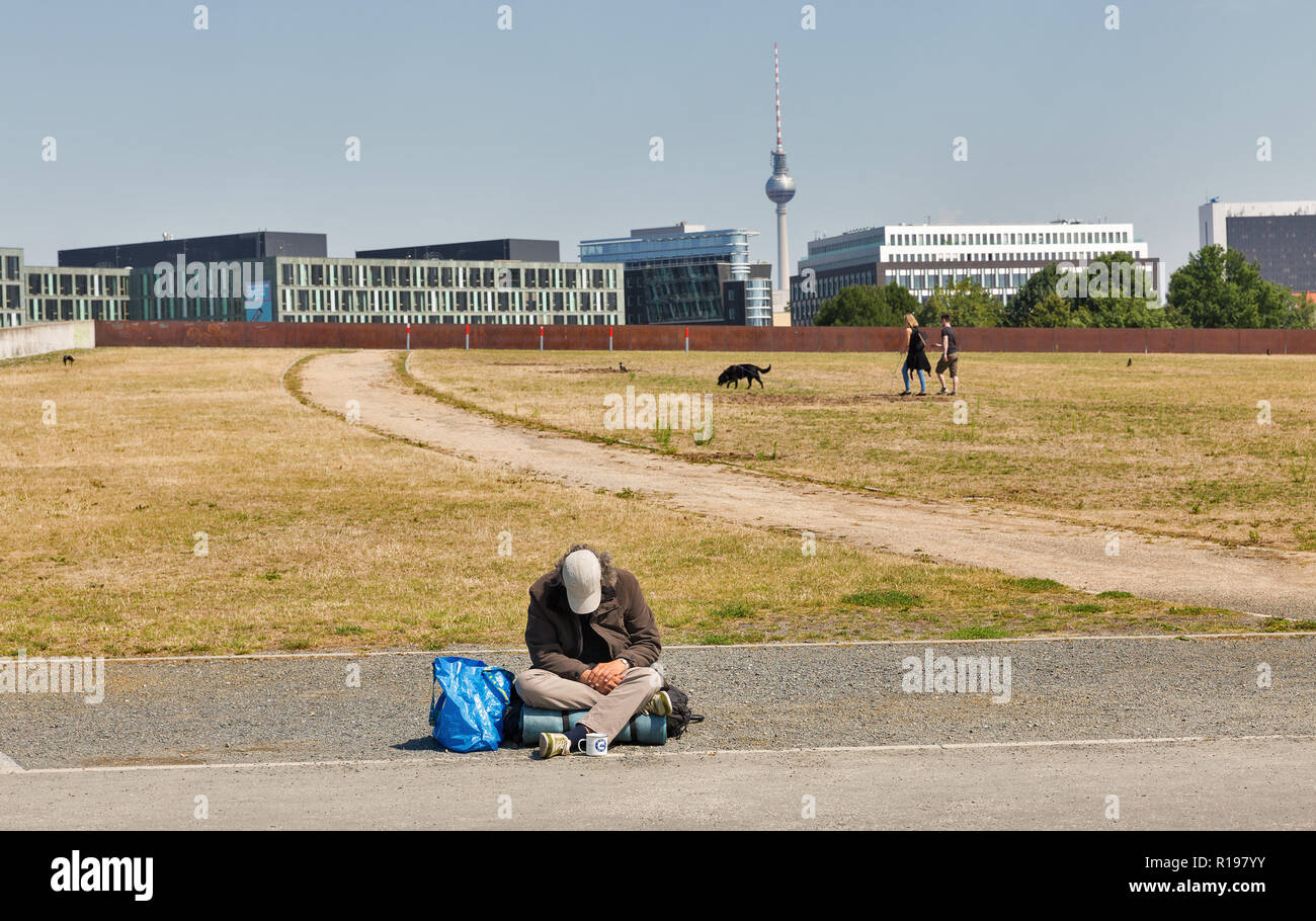 BERLIN, GERMANY - JULY 13, 2018: Unrecognized homeless man begging in Spreebogenpark. Government buildings and Fernsehturm TV tower in the background. Stock Photo