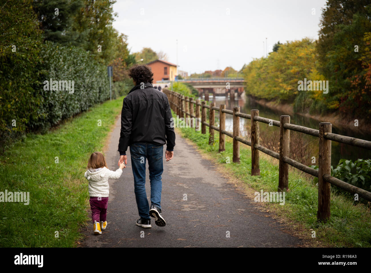 young dad and toddler girl strolling on a country footpath along the canal. Stock Photo