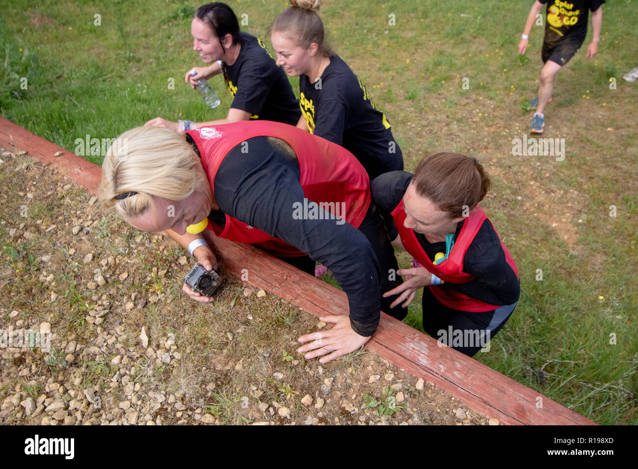Obstacle course runners climbing a wall Stock Photo Alamy