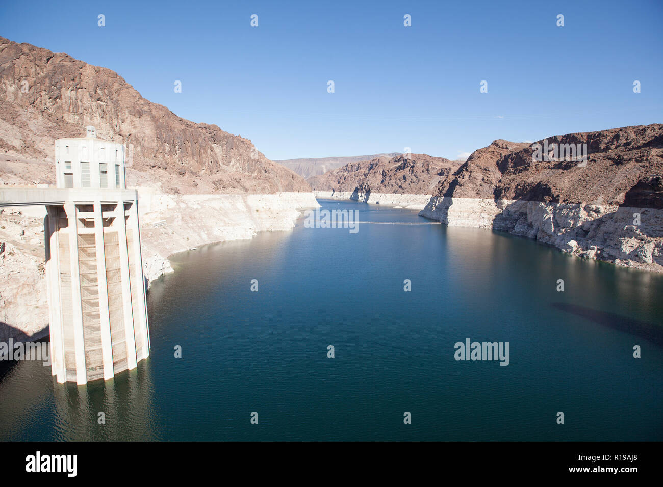 View of Lake Mead  behind Hoover Dam and the water towers. The cliffs discoloration shows how much Lake Mead has receded in level Stock Photo