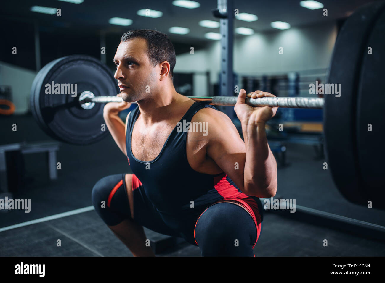 Muscular powerlifter doing squats with barbell in gym. Weightlifting  workout, powerlifting training in sport club Stock Photo - Alamy