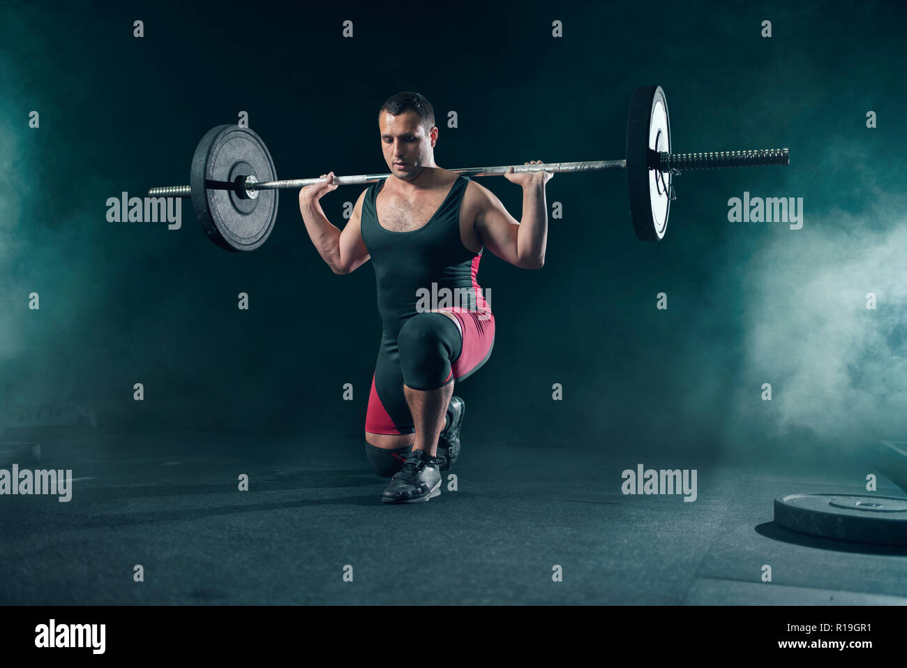 Strong weight lifter doing squats with a barbell in gym, deadlift ...