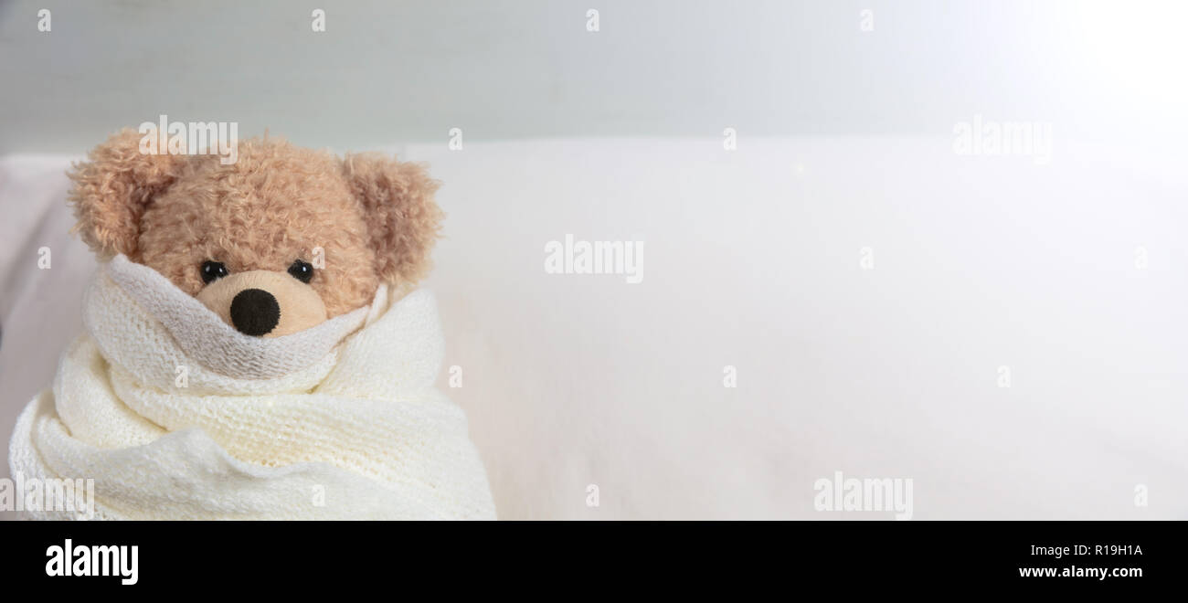 cKid in bed in a cold day. Cute teddy covered with a warm blanket, resting in bed, banner, copy space Stock Photo