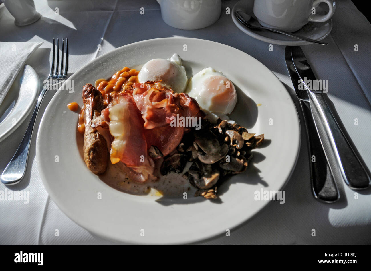 An Australian cooked breakfast of egg, sausage, bacon, mushrooms baked