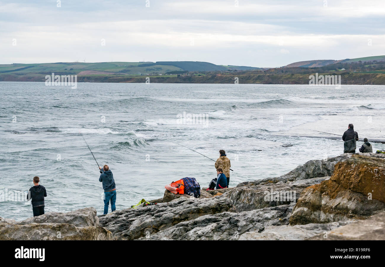 Torness, East Lothian, Scotland, United Kingdom, 10th November 2018. UK Weather: Despite the storm on the UK's West coastline, Eastern Scotland is mild with only a slight breeze. People fishing from the rocks next to Torness nuclear power station Stock Photo