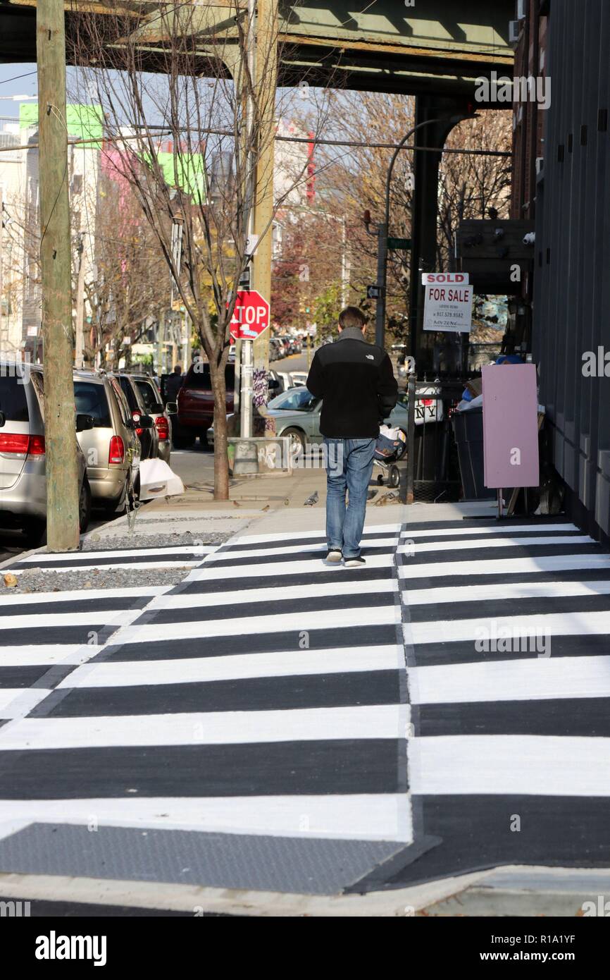 New York, NY, USA. 10 Nov., 2018. A stretch of a Brooklyn, New York sidewalk, has been transformed into a checkerboard of black and white squares across a patch of pavement outside a fancy new apartment building and store RISK Boutique and Gallery in the rapidly gentrified neighborhood of Bushwick. The Department of Transportation says people cannot legally paint sidewalks and unauthorized artistry typically receives a fine, with property owners usually get 30 days to remove their work before an official penalty follows. © 2018 G. Ronald Lopez/DigiPixsAgain.us/Alamy Live News Stock Photo