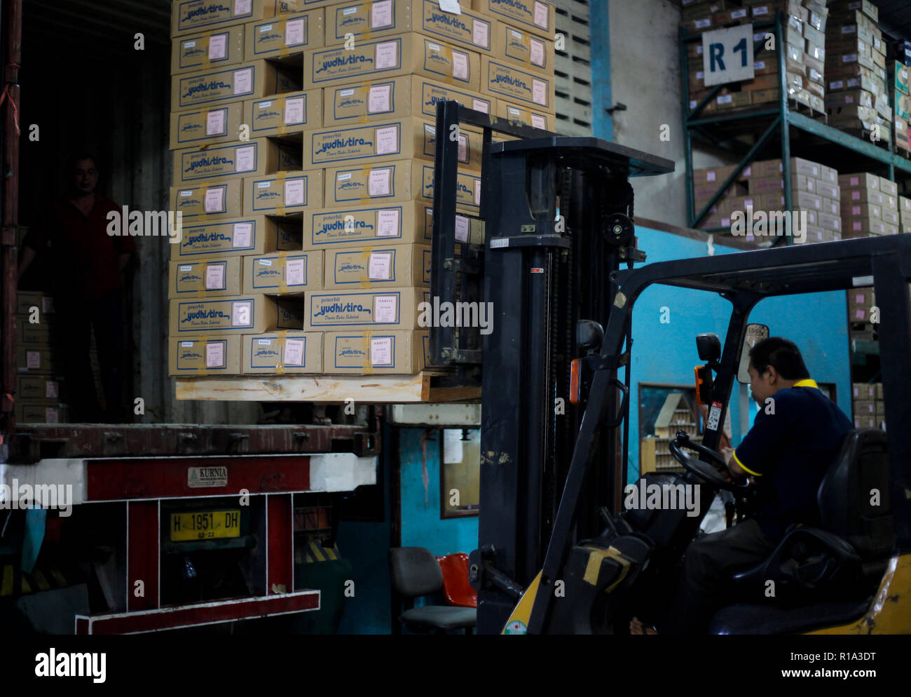 A worker seen lifting a cardboard box into a container truck using a ...