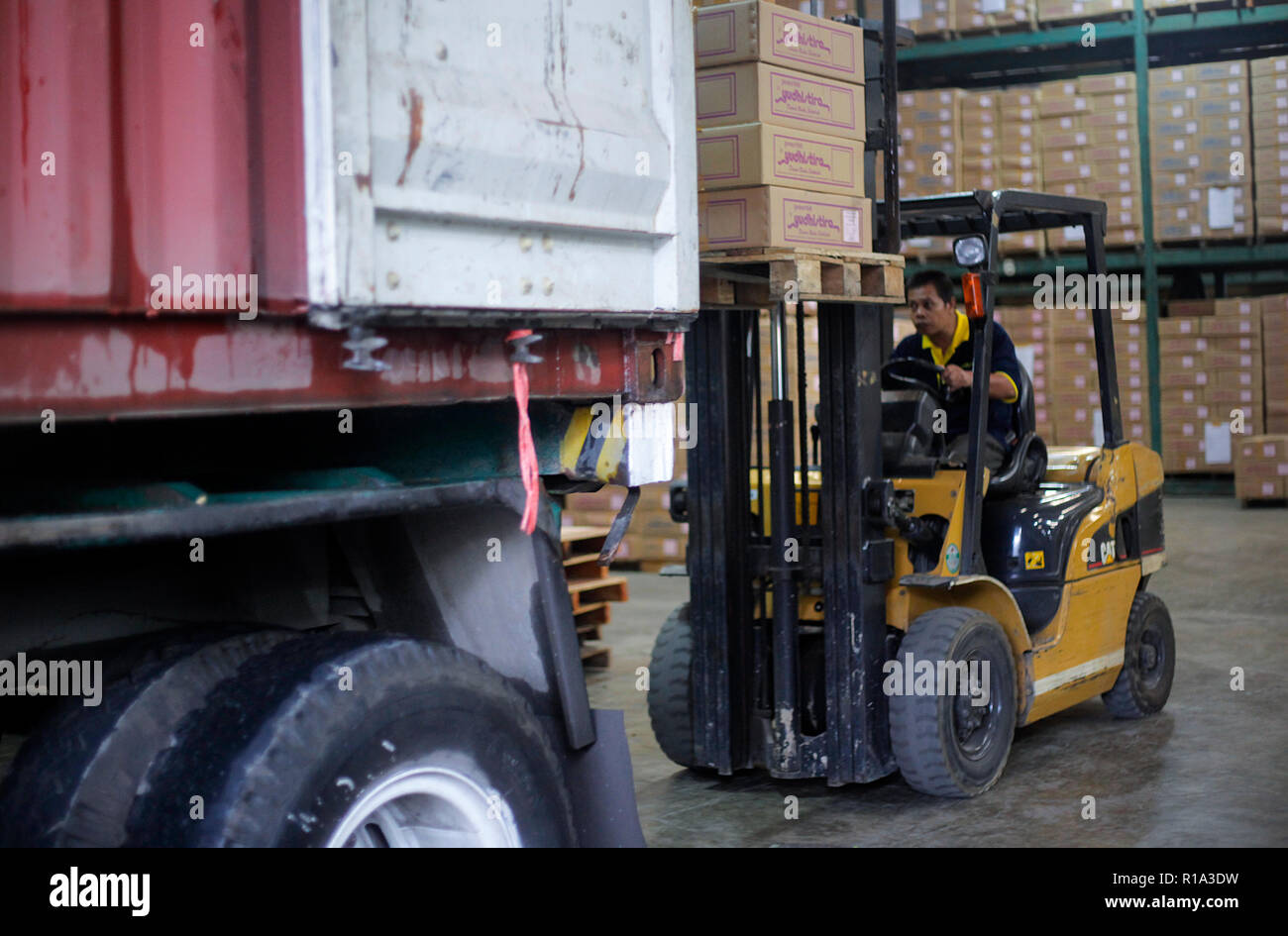 A worker seen lifting a cardboard box into a container truck using a ...