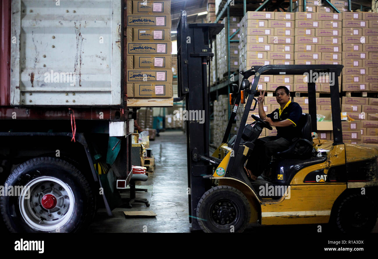 A worker seen lifting a cardboard box into a container truck using a ...