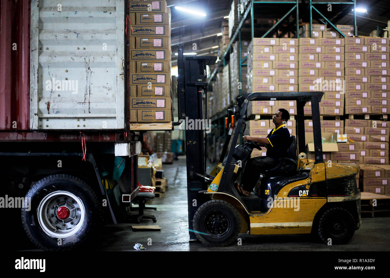 A worker seen lifting a cardboard box into a container truck using a ...