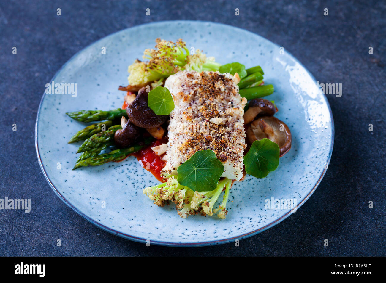 Halibut with hazelnut crust with roast red pepper sauce, asparagus, cauliflower and shiitake mushrooms Stock Photo