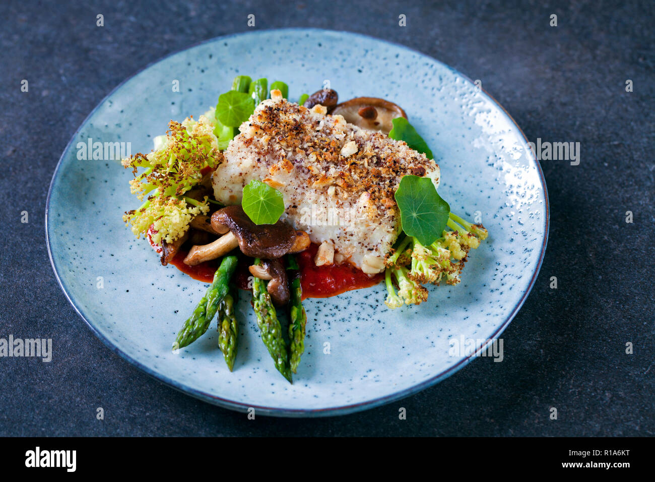 Halibut with hazelnut crust with roast red pepper sauce, asparagus, cauliflower and shiitake mushrooms Stock Photo