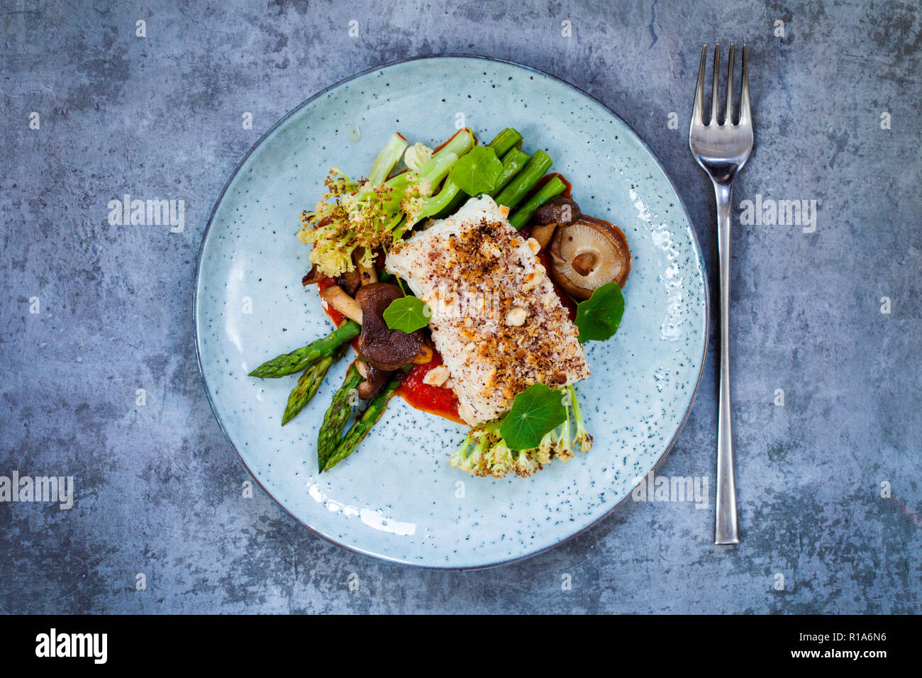 Halibut with hazelnut crust with roast red pepper sauce, asparagus, cauliflower and shiitake mushrooms Stock Photo