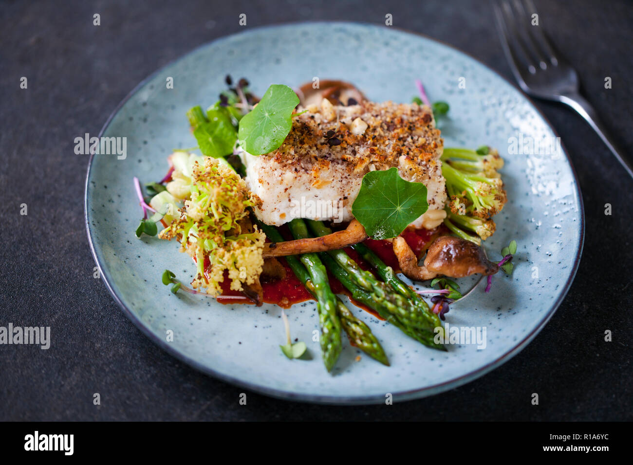 Halibut with hazelnut crust with roast red pepper sauce, asparagus, cauliflower and shiitake mushrooms Stock Photo