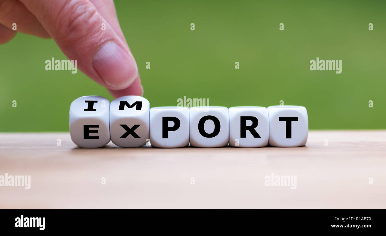Hand is turning a dice and changes the word 'import' to 'export' Stock Photo