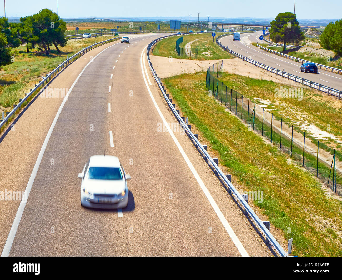 A white car crossing a european highway at a sunny day. Stock Photo