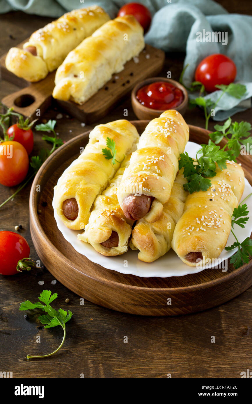 Sausage in Dough in rustic style on wooden table. Copy space Stock