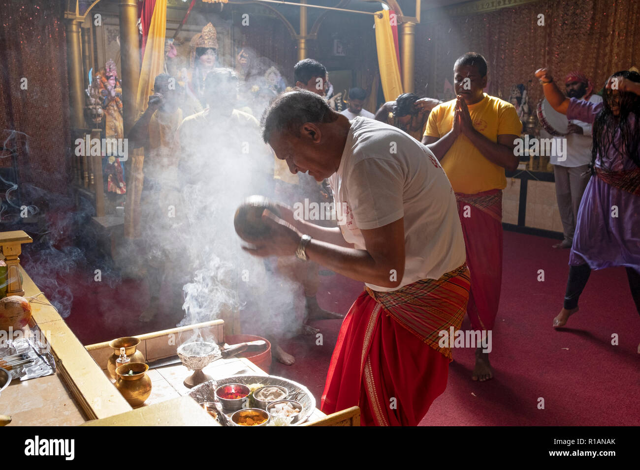 A Hindu devotee  makes a food offering to the goddess Kali at a Shakti Hindu temple in Queens, New York City. Stock Photo