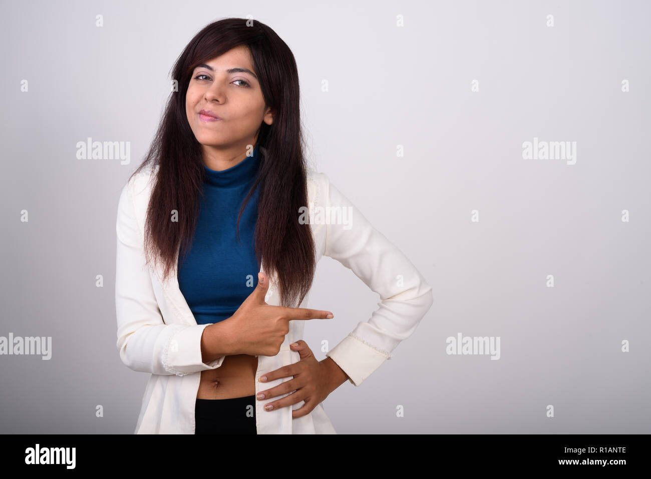 Studio shot of young Persian businesswoman pointing to the side  Stock Photo