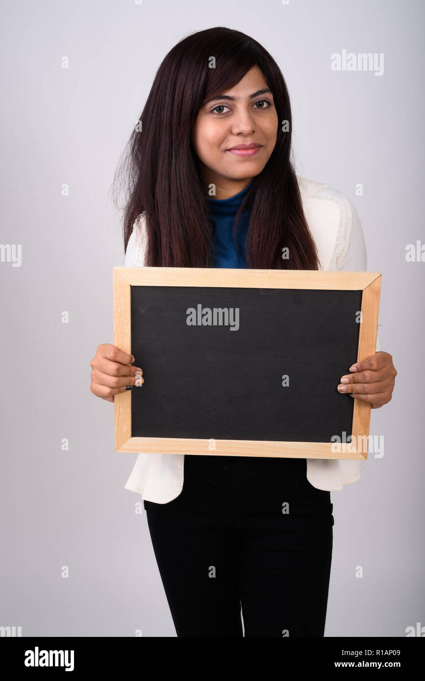 Studio shot of young Persian businesswoman standing while holdin Stock Photo